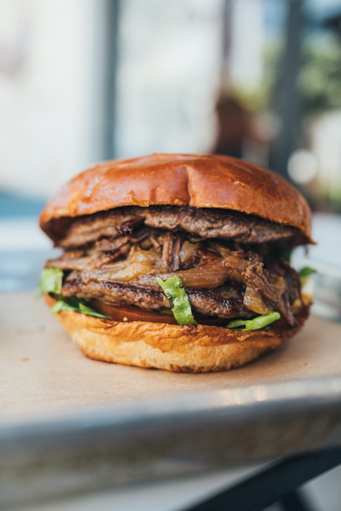 Pulled Pork Burger auf Brioche-Bun mit karamellisierten Zwiebeln und frischem Salat