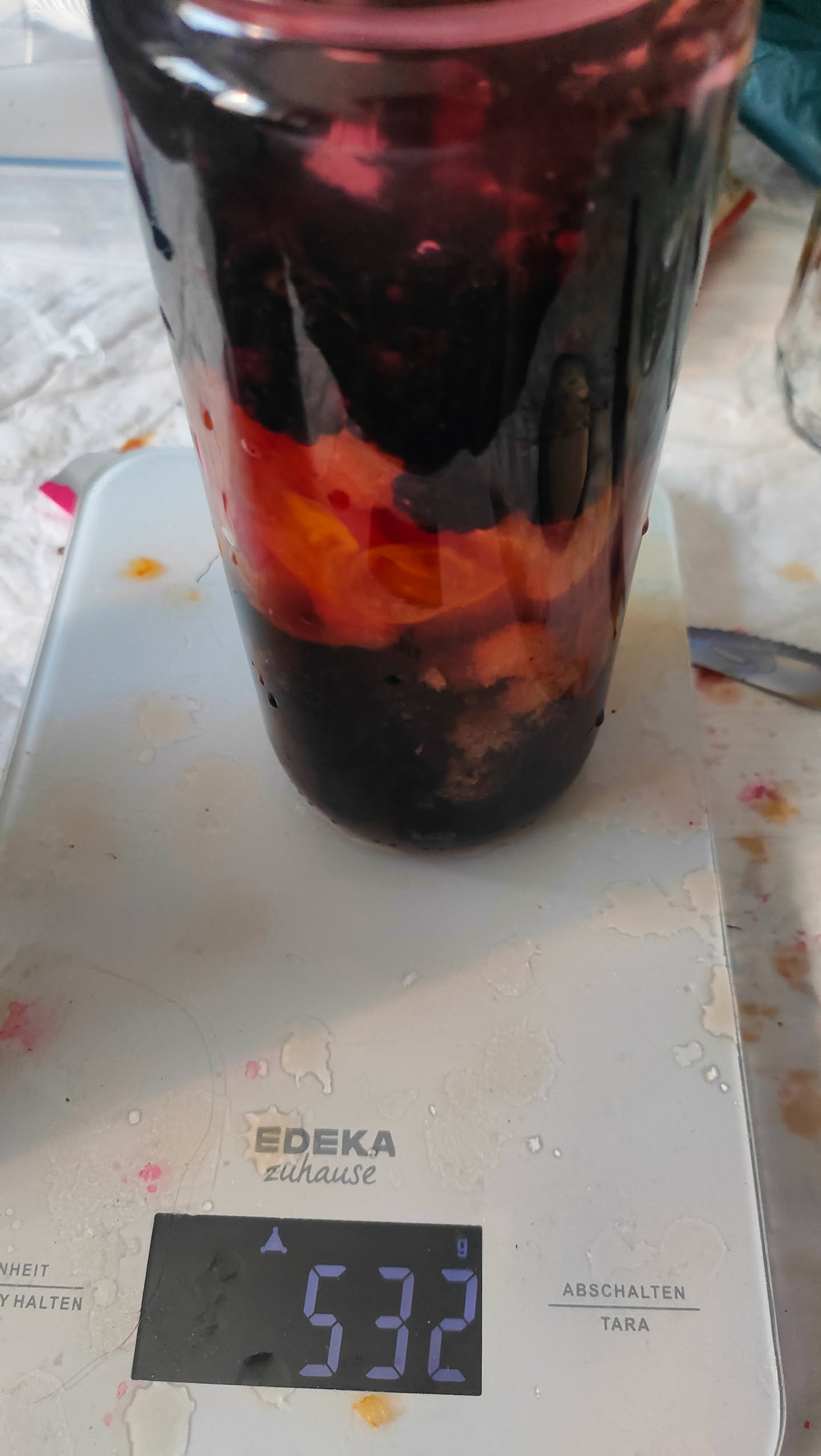 Kleineres Glas mit Brombeeren und Kirschpflaumen in Alkohol, Waage zeigt 532 Gramm