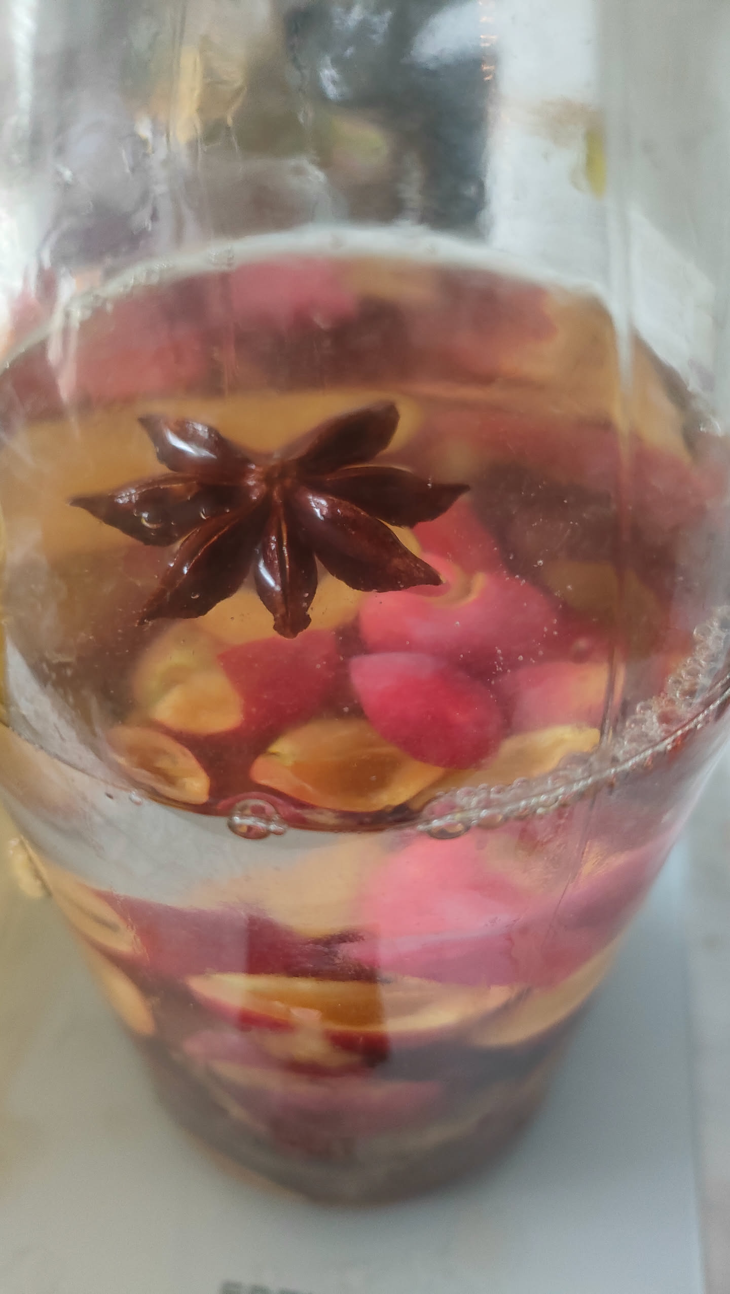 Nahaufnahme eines Sternanis, der im Alkohol zwischen Kirschpflaumenstücken schwimmt