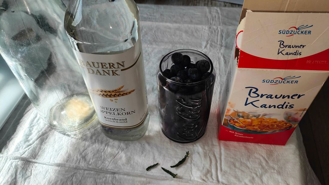 Alle Zutaten für den Schlehenlikör aufgereiht: Doppelkorn, Schlehen im Glas, brauner Kandis, Schafgarbe