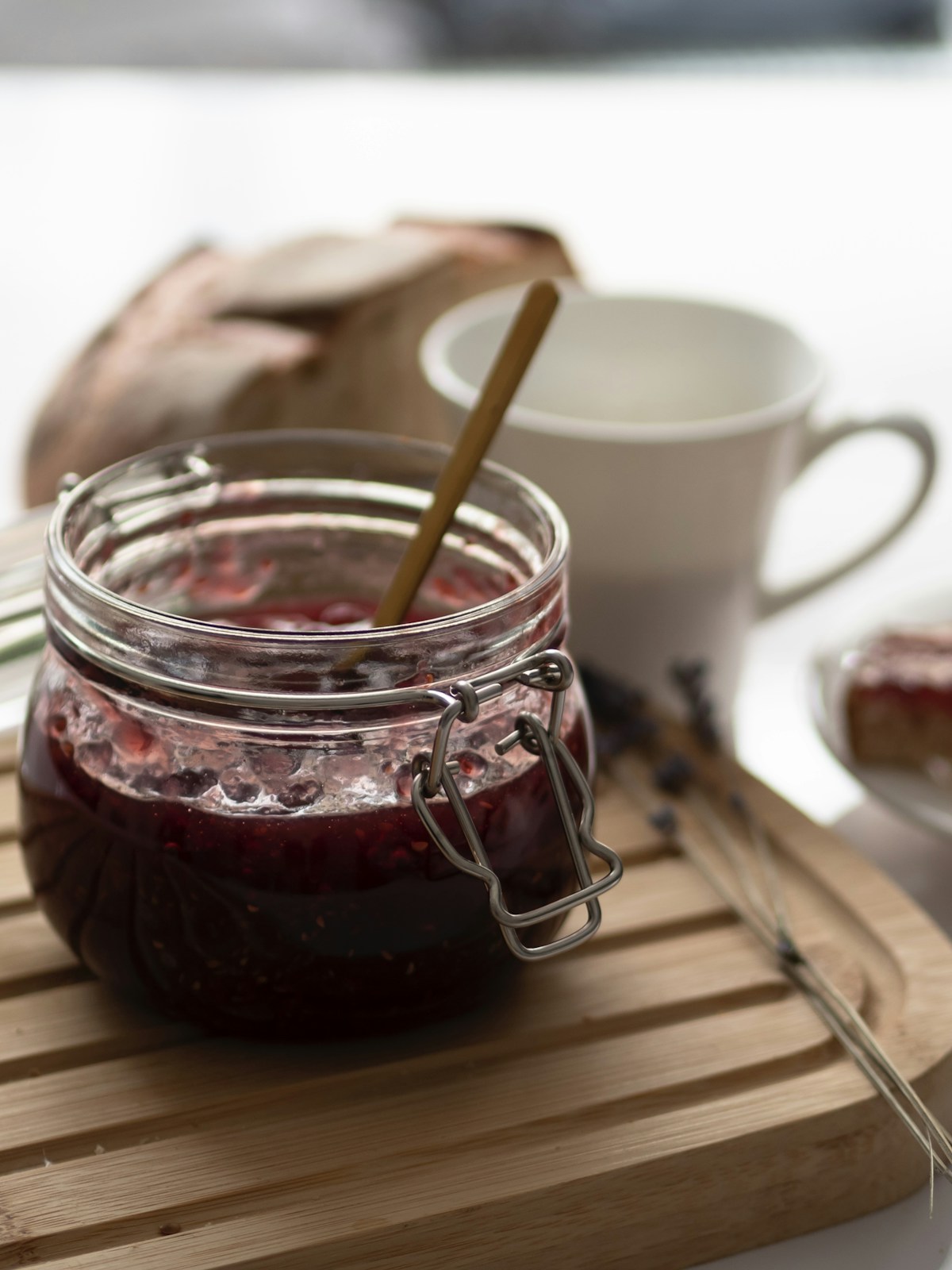 Hagebutten-Marmelade im Bügelglas mit Holzlöffel auf Schneidebrett