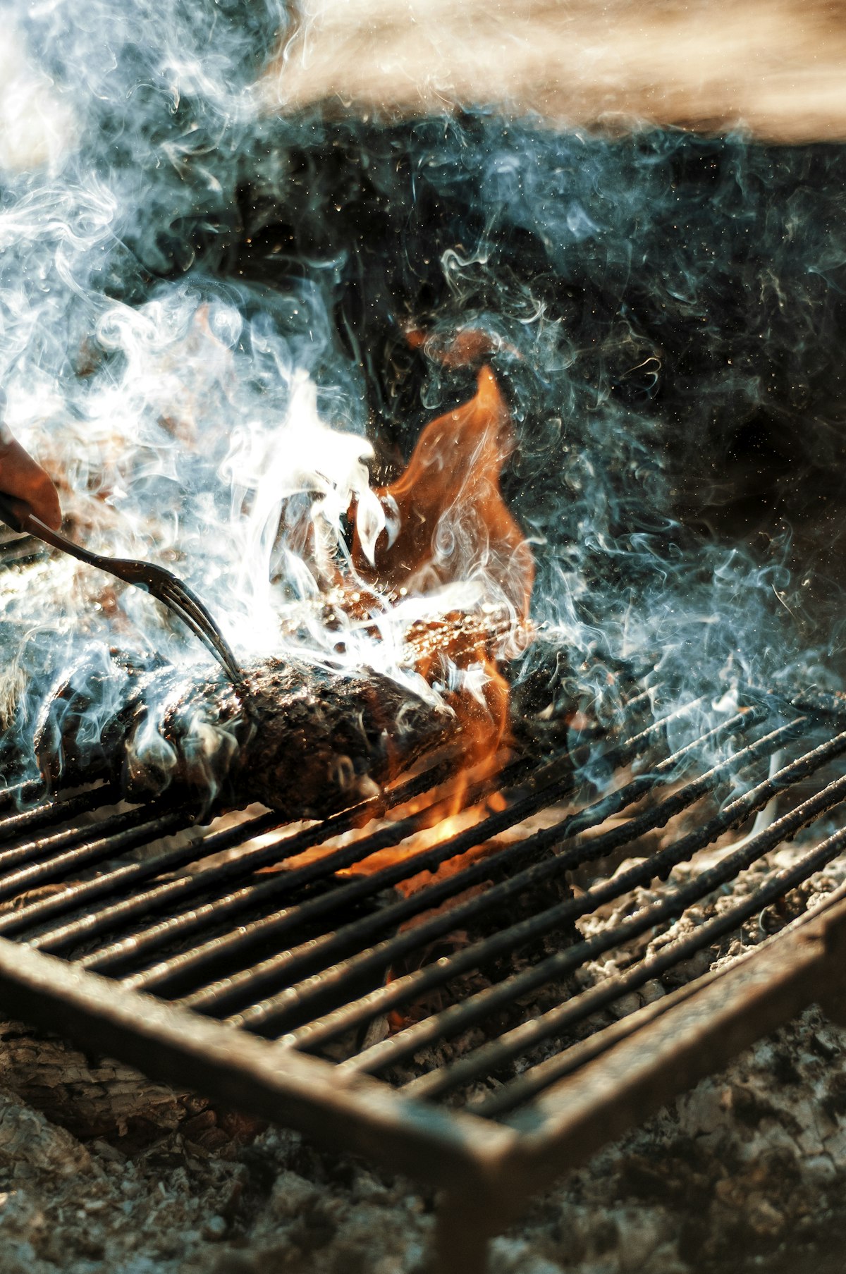 Fisch auf dem Grillrost über offenem Feuer mit Flammen und Rauch