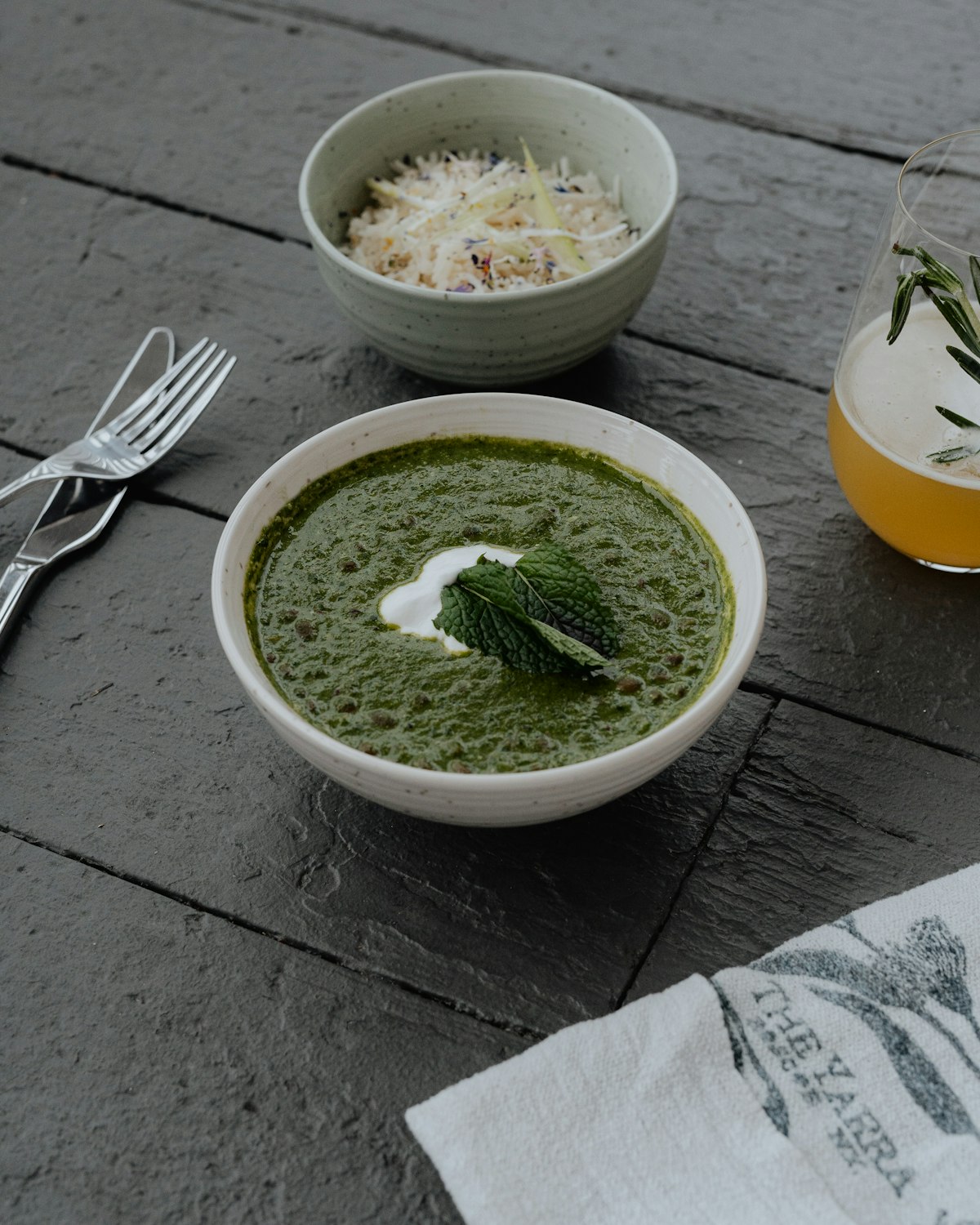 Cremige grüne Brennnessel-Suppe in weißer Schüssel mit Sauerrahm und frischen Kräutern