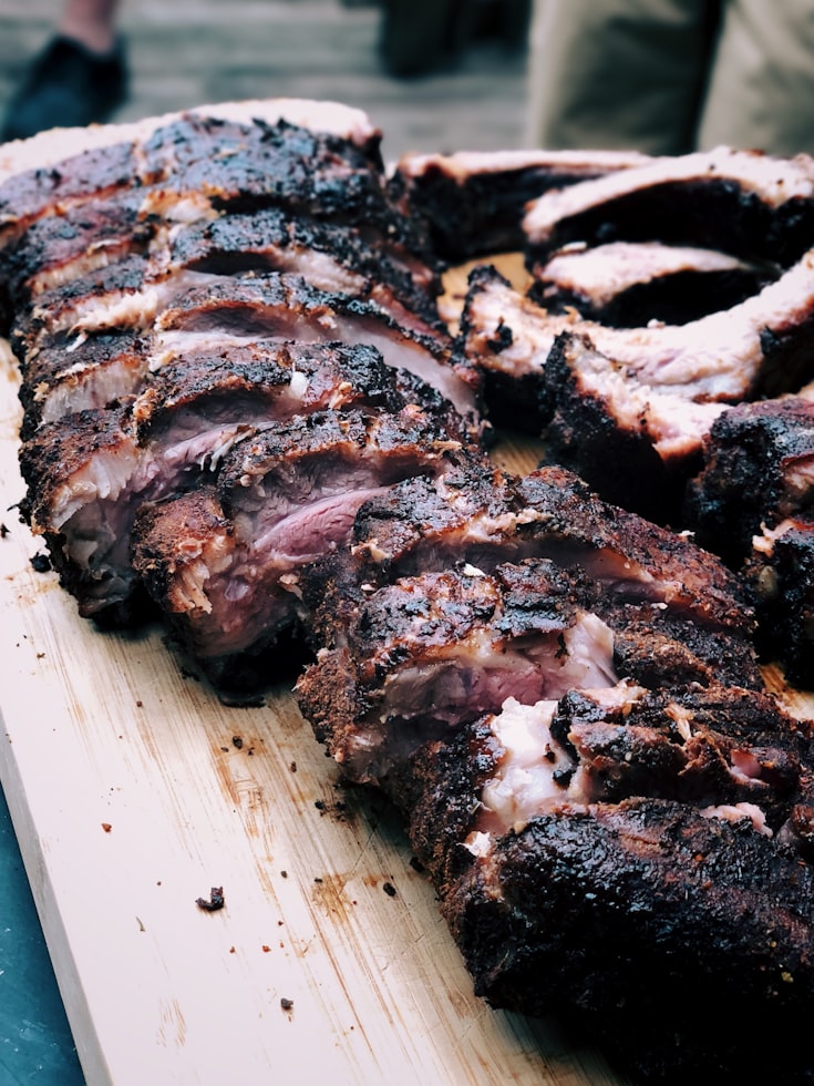 Gegrillte Spareribs auf rustikalem Holzbrett, aufgeschnitten