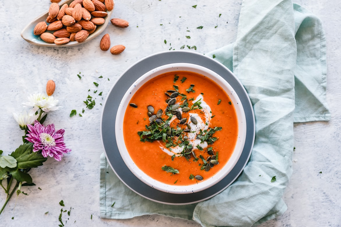 Cremige Kürbissuppe in orangefarbener Schüssel mit Kürbiskernen
