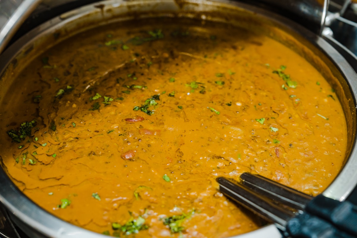 Linsen-Curry im Topf, cremige orangefarbene Sauce mit frischen Kräutern