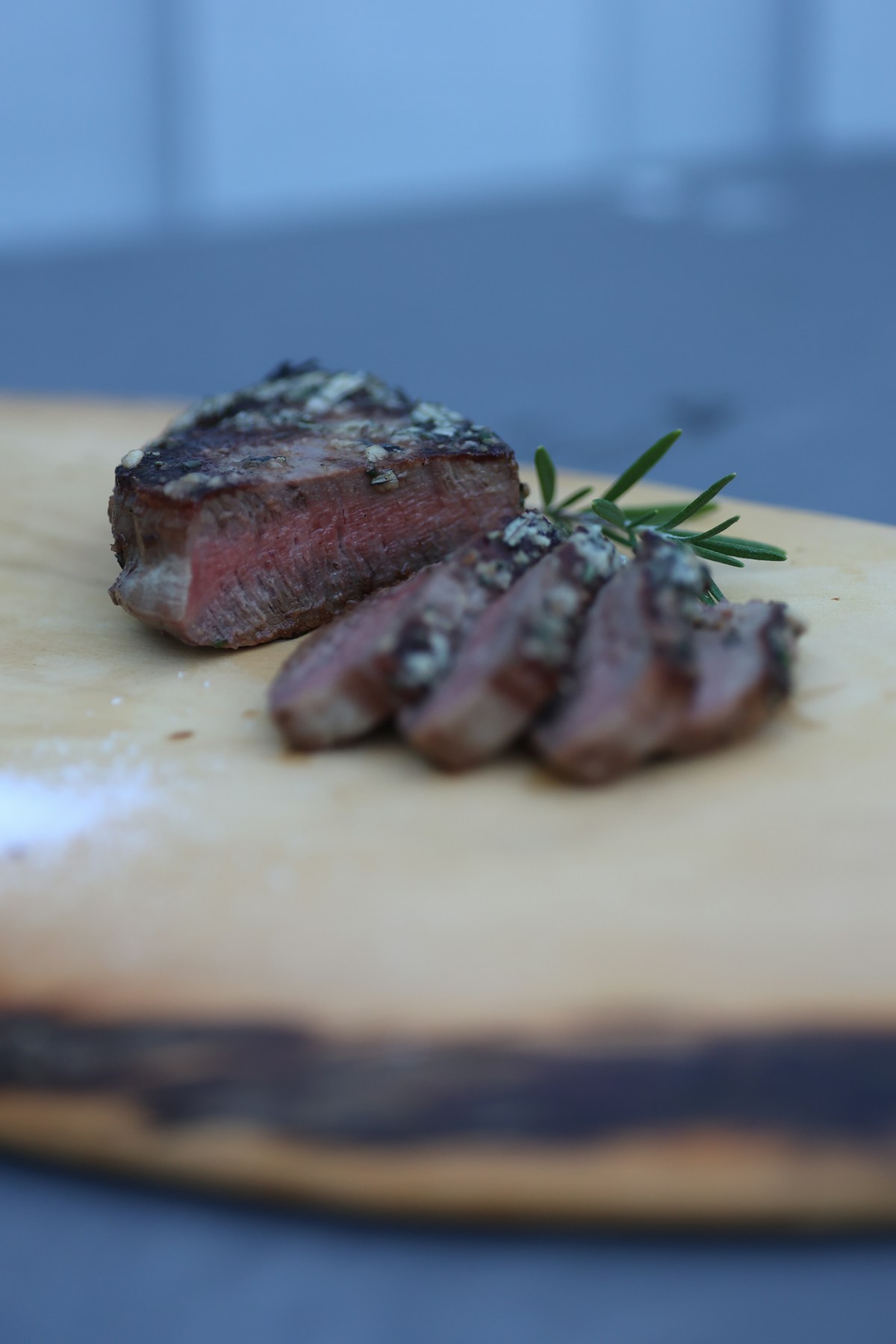 Aufgeschnittenes Wildsteak mit Rosmarin auf Holzbrett