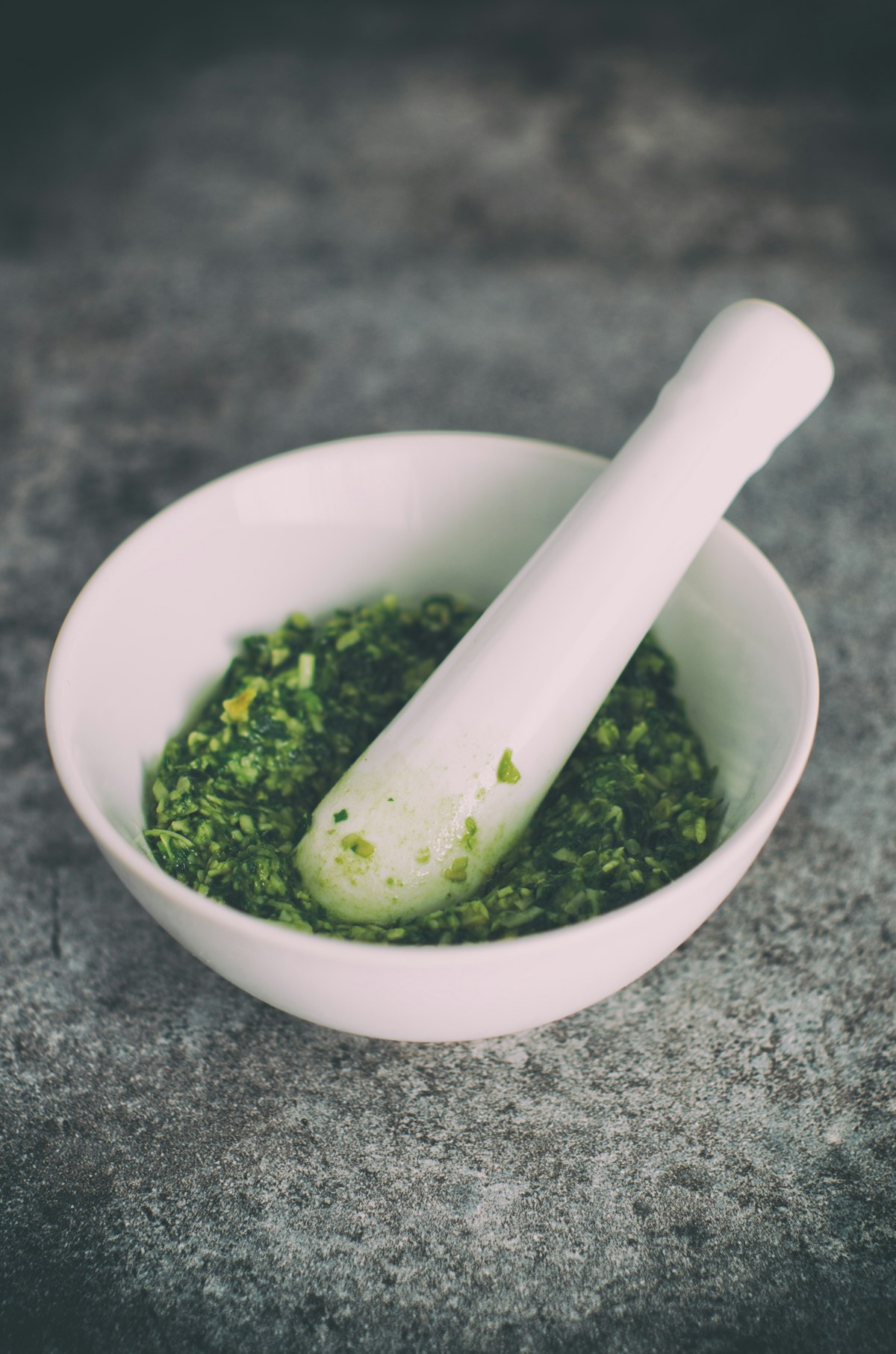 Grünes Wildkraut-Pesto in einem Steinmörser mit Basilikumblättern