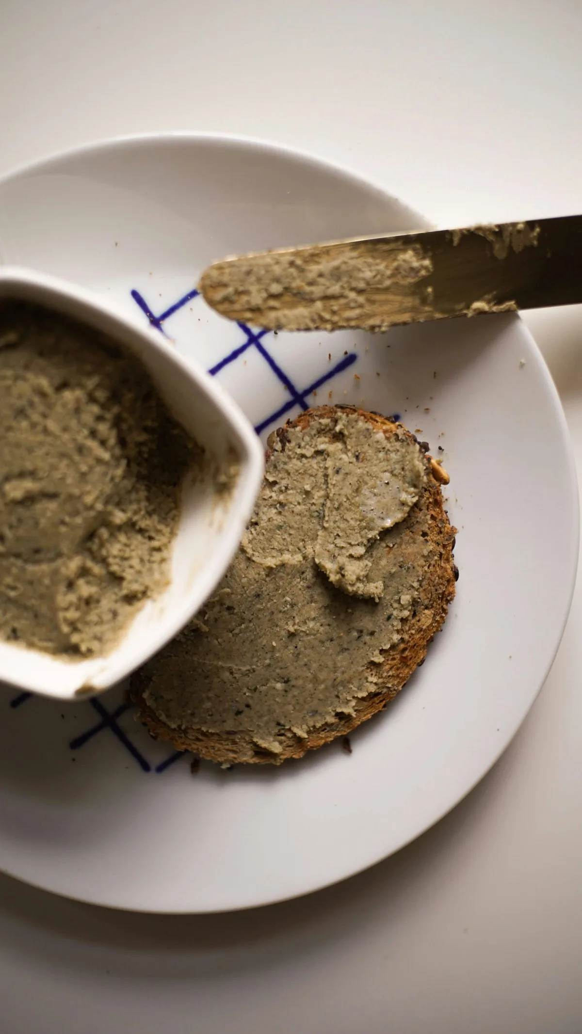 Dunkelgrüner Kräuter-Aufstrich auf einer Brotscheibe, Messer liegt daneben