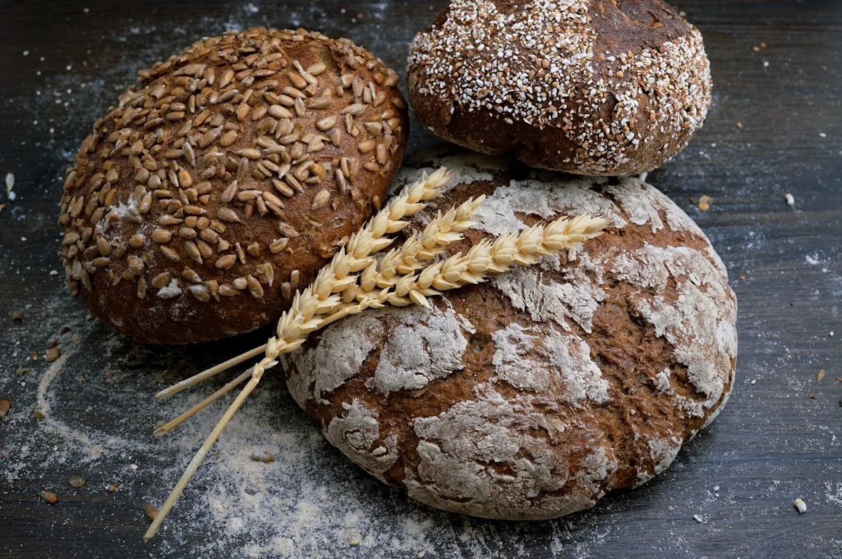 Drei rustikale Brotlaibe auf dunklem Holz