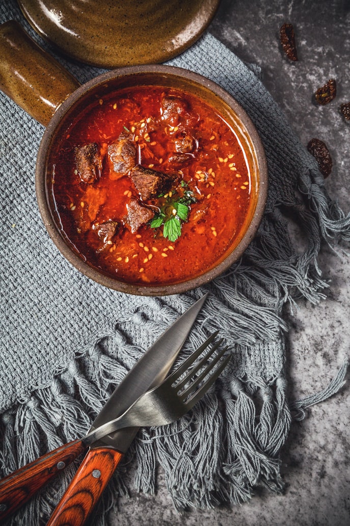 Wildschwein-Gulasch in einer rustikalen Tonschüssel – dunkelrote Sauce mit Fleischstücken