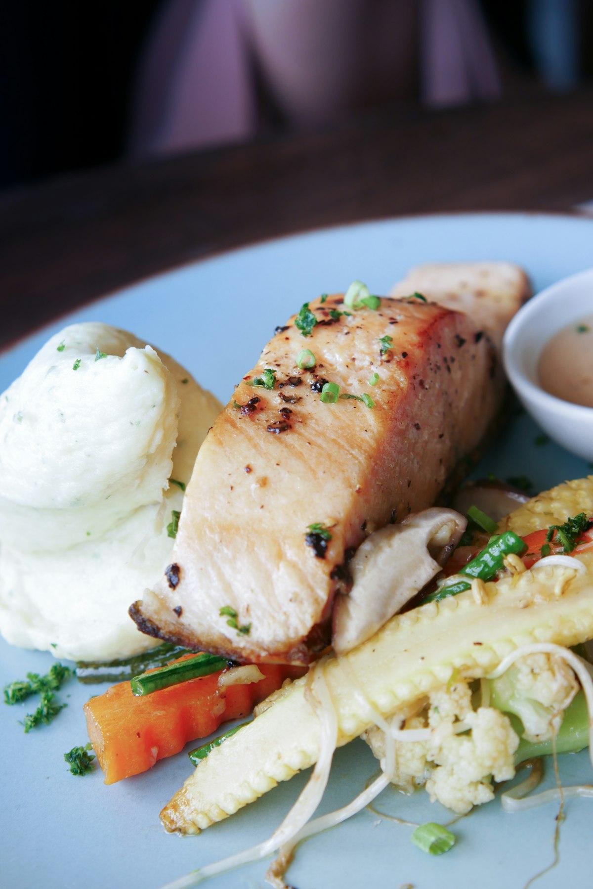 Gebratenes Fischfilet mit goldbrauner Kruste auf blauem Teller mit Kartoffelpüree und Gemüse