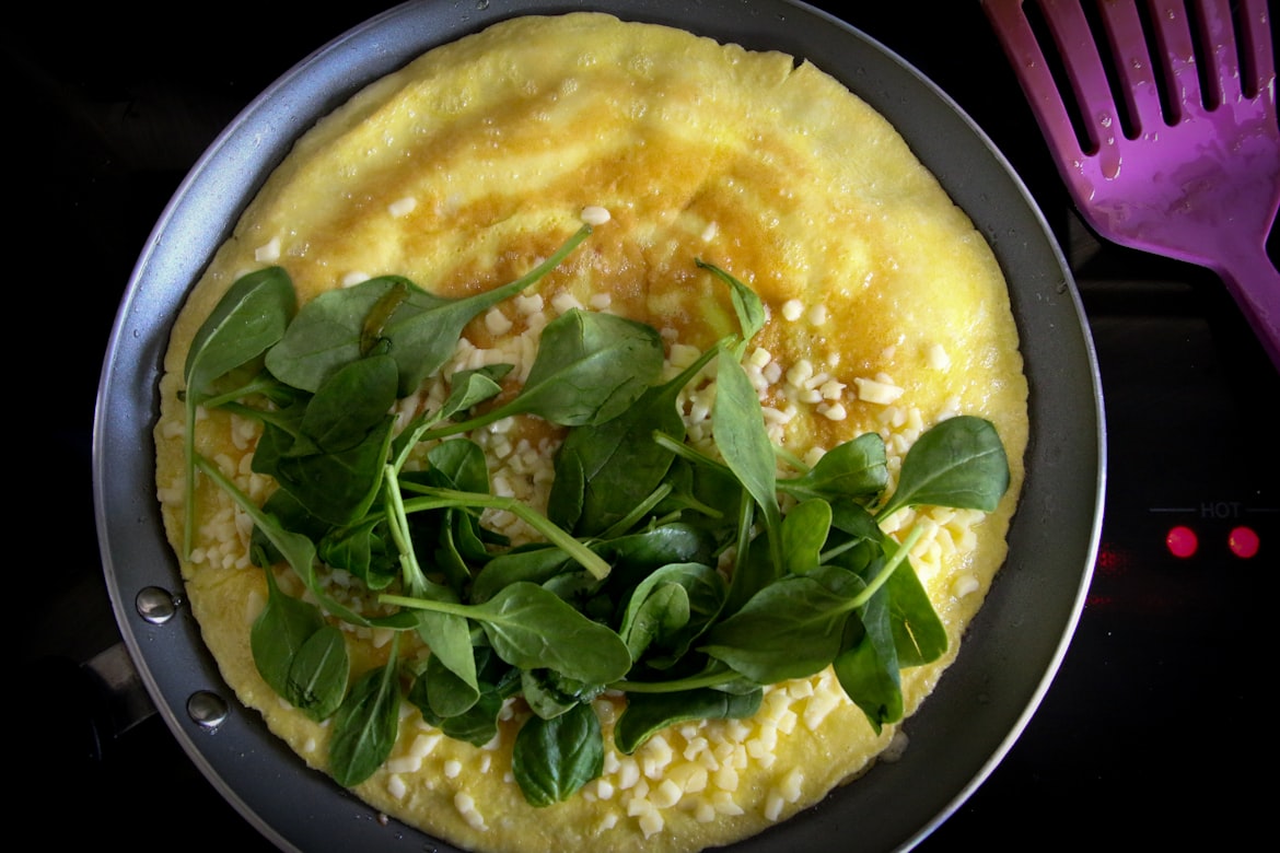 Frittata mit Kräutern und Käse in der Pfanne beim Stocken